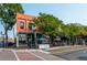 Two-story orange brick building featuring outdoor seating, decorative awnings, street-side trees, and a vintage light post at 5211 Dover St, Arvada, CO 80002