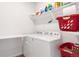 Bright laundry room features newer appliances and practical storage shelves at 8582 Cheraw St, Littleton, CO 80125