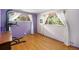 Unique bedroom with hardwood floors, bright purple accent wall, sheer curtains, and natural light from the large windows at 3900 Garland St, Wheat Ridge, CO 80033