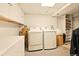 Bright laundry room includes modern washer and dryer, white cabinetry, and ample lighting at 12234 W Saratoga Ave, Morrison, CO 80465