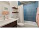 Modern bathroom with blue tiled shower, dark wood vanity, and white countertop at 474 N Inca St, Denver, CO 80204