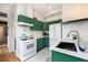 Well-lit kitchen with green cabinets, a white gas range, stainless steel appliances, and marble countertops at 474 N Inca St, Denver, CO 80204
