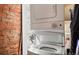 A clean, white stacked washer and dryer unit is next to a brick wall at 474 N Inca St, Denver, CO 80204
