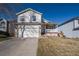 Two-story home with a two-car garage, a white porch, and a well-maintained front yard under a clear blue sky at 4931 S Danube St, Aurora, CO 80015