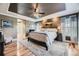 This main bedroom features a tray ceiling, many windows, a large bed, and wood floors at 5572 Fullerton Cir, Highlands Ranch, CO 80130