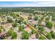 Aerial view of a residential neighborhood with green trees, a school, and a lake, indicating a Gathering-friendly location at 8357 Dudley Ct, Arvada, CO 80005