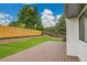 Large wooden deck overlooking a large backyard with grass, privacy fence, and retaining wall at 8357 Dudley Ct, Arvada, CO 80005
