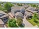 Aerial view of a gray two-story home with a three-car garage, mature landscaping and a long driveway at 8677 S Buchanan Way, Aurora, CO 80016