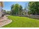 Expansive backyard featuring a lush green lawn, stone retaining wall, mature trees and split rail fence at 8677 S Buchanan Way, Aurora, CO 80016
