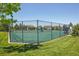 Fenced community tennis court with green surface and residential homes in the background at 8677 S Buchanan Way, Aurora, CO 80016