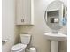 Comfortable bathroom featuring a pedestal sink, round mirror and built-in storage at 6765 S Old Hammer Ct, Aurora, CO 80016