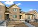 Charming townhome featuring stone accents, a fenced front yard, and solar panels on the roof at 6765 S Old Hammer Ct, Aurora, CO 80016