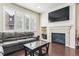 Comfortable living room features a stone fireplace, large windows, and a dark leather couch at 6765 S Old Hammer Ct, Aurora, CO 80016