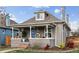 Charming home with a inviting covered porch, gray paint, beautiful landscaping, and a new blue front door at 1194 S Washington St, Denver, CO 80210