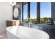 Spa-like bathroom with a modern soaking tub, brass fixtures and a large window overlooking the yard at 5358 Lions Paw St, Castle Rock, CO 80104