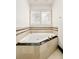 Corner bathtub with stone tile surround and window at 2 Cherry Hills Farm Dr, Cherry Hills Village, CO 80113