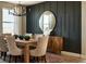 Modern dining room featuring wood table, upholstered chairs, chandelier, and a dark accent wall at 5629 Farrier Pt, Castle Rock, CO 80104