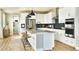 Bright kitchen with white cabinets, stainless steel appliances, a large island with seating, and modern pendant lighting at 5629 Farrier Pt, Castle Rock, CO 80104