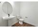 Modern powder room with pedestal sink, round mirror, and wood-look flooring at 5629 Farrier Pt, Castle Rock, CO 80104