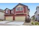 Modern two-story townhome featuring red siding, a two-car garage, and well-maintained landscaping at 17855 E 103Rd Ave, Commerce City, CO 80022
