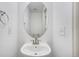 Compact half bath featuring a pedestal sink, oval mirror, and clean white walls at 19153 E 51St Ave, Denver, CO 80249