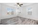 Bright bedroom with wood-look flooring, ceiling fan, and two windows overlooking the neighborhood at 19153 E 51St Ave, Denver, CO 80249