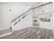 Open-concept living space with modern staircase, wood floors, and a view into the adjacent kitchen at 19153 E 51St Ave, Denver, CO 80249