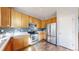 Well-lit kitchen with stainless steel appliances, wooden cabinets, and mosaic backsplash at 6898 W Rockland Pl, Littleton, CO 80128