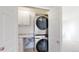 Laundry closet with stacked washer and dryer unit and storage, adjacent to a carpeted bedroom at 6898 W Rockland Pl, Littleton, CO 80128