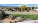 Playground with green turf, playground equipment and benches, surrounded by grass and trees at 6898 W Rockland Pl, Littleton, CO 80128