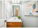 Bright bathroom with wood vanity, white sink, and modern lighting and mirror, freshly painted at 5174 S Ukraine St, Aurora, CO 80015