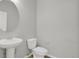 Bathroom with toilet, sink, oval mirror, and wood-style flooring at 1775 Aspen Meadows Cir, Denver, CO 80260