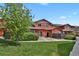 Charming red townhome with lush green lawn, mature tree, and inviting entrance at 1775 Aspen Meadows Cir, Denver, CO 80260