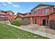 Red townhome exterior featuring a well-maintained lawn and landscaped pathway at 1775 Aspen Meadows Cir, Denver, CO 80260