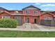 Inviting red townhome exterior showcasing a landscaped front yard and modern entrance at 1775 Aspen Meadows Cir, Denver, CO 80260