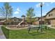 A community playground with a slide and swings in a grassy area at 1775 Aspen Meadows Cir, Denver, CO 80260