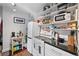 Compact kitchen with stainless steel appliances, open shelving, and white cabinets with black countertops at 3835 N Raleigh St, Denver, CO 80212