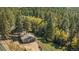 Aerial view of a home on a wooded lot with mature trees and a detached two car garage at 25728 Stanley Park Rd, Evergreen, CO 80439