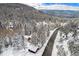 Aerial view of a home and the road out front covered in snow and evergreen trees at 25728 Stanley Park Rd, Evergreen, CO 80439