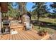 Inviting wooden deck area with a grill, an Adirondack chair and a view of the yard and a quaint greenhouse at 25728 Stanley Park Rd, Evergreen, CO 80439
