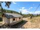 Exterior view of a home situated on a spacious lot, surrounded by mature trees and mountain views at 25728 Stanley Park Rd, Evergreen, CO 80439