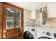 Laundry room with a door to the exterior, modern washer and dryer and storage at 25728 Stanley Park Rd, Evergreen, CO 80439