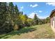 Expansive, well-maintained lawn with mature trees and landscaping, bordering the house at 25728 Stanley Park Rd, Evergreen, CO 80439