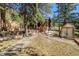 Scenic view of a stone pathway leading to a charming home, complemented by lush greenery and a greenhouse at 25728 Stanley Park Rd, Evergreen, CO 80439