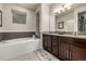 Relaxing bathroom features a luxurious soaking tub, double vanity, stylish fixtures, and neutral tilework at 2110 W 67Th Pl, Denver, CO 80221