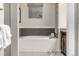 Bathroom featuring a soaking tub with decorative tile surround, window, and sleek fixtures for a relaxing experience at 2110 W 67Th Pl, Denver, CO 80221