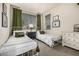 Charming bedroom featuring twin beds, decorative pillows, stylish nightstand and dark green curtains at 2110 W 67Th Pl, Denver, CO 80221