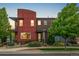Modern townhome with a red exterior, brick accents, and well-maintained landscaping at 2110 W 67Th Pl, Denver, CO 80221