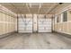 Spacious unfinished two car garage with unfinished walls, concrete floor, and two white garage doors at 2110 W 67Th Pl, Denver, CO 80221
