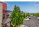 View of a modern home and street with mature trees and mountain views on a partly cloudy day at 2110 W 67Th Pl, Denver, CO 80221